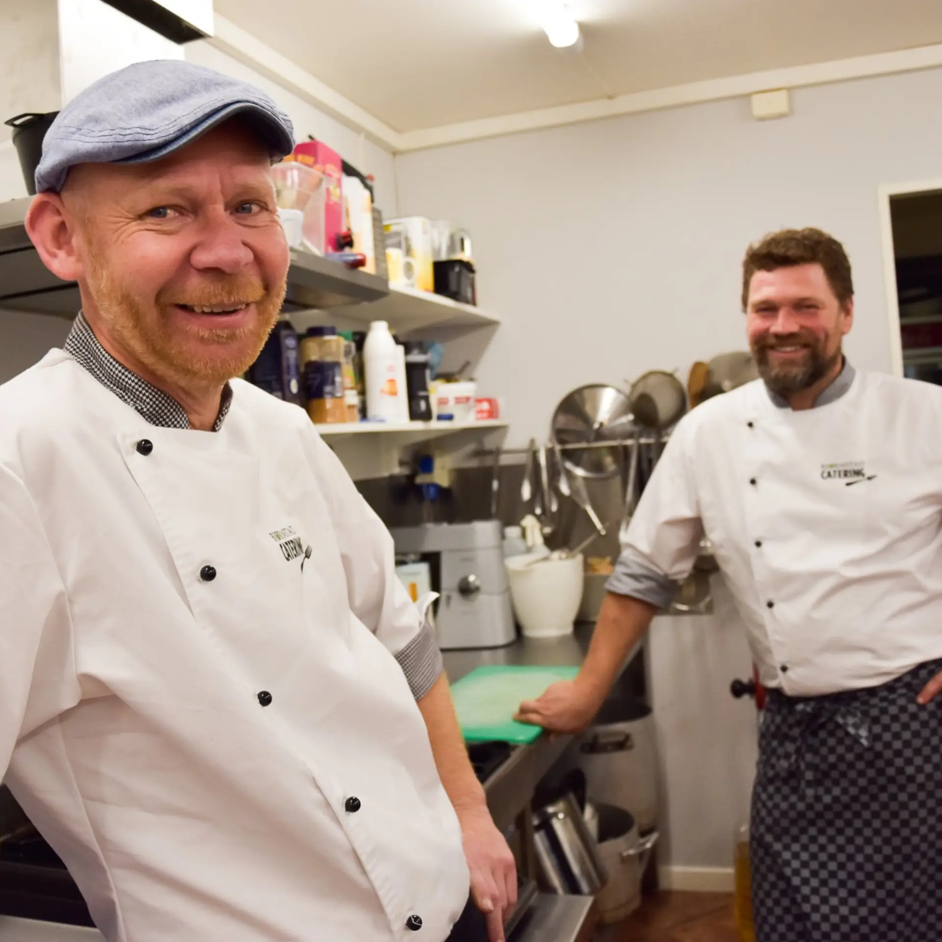 To kokker fra Bjørnstad Catering smiler på kjøkkenet